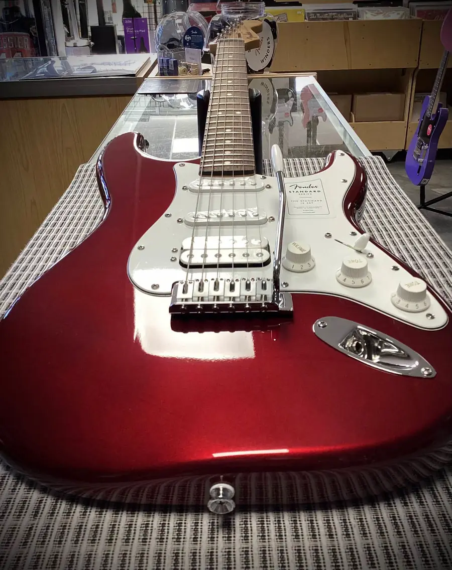 Red Fender Standard Series Stratocaster on the counter, vinyl racks behind